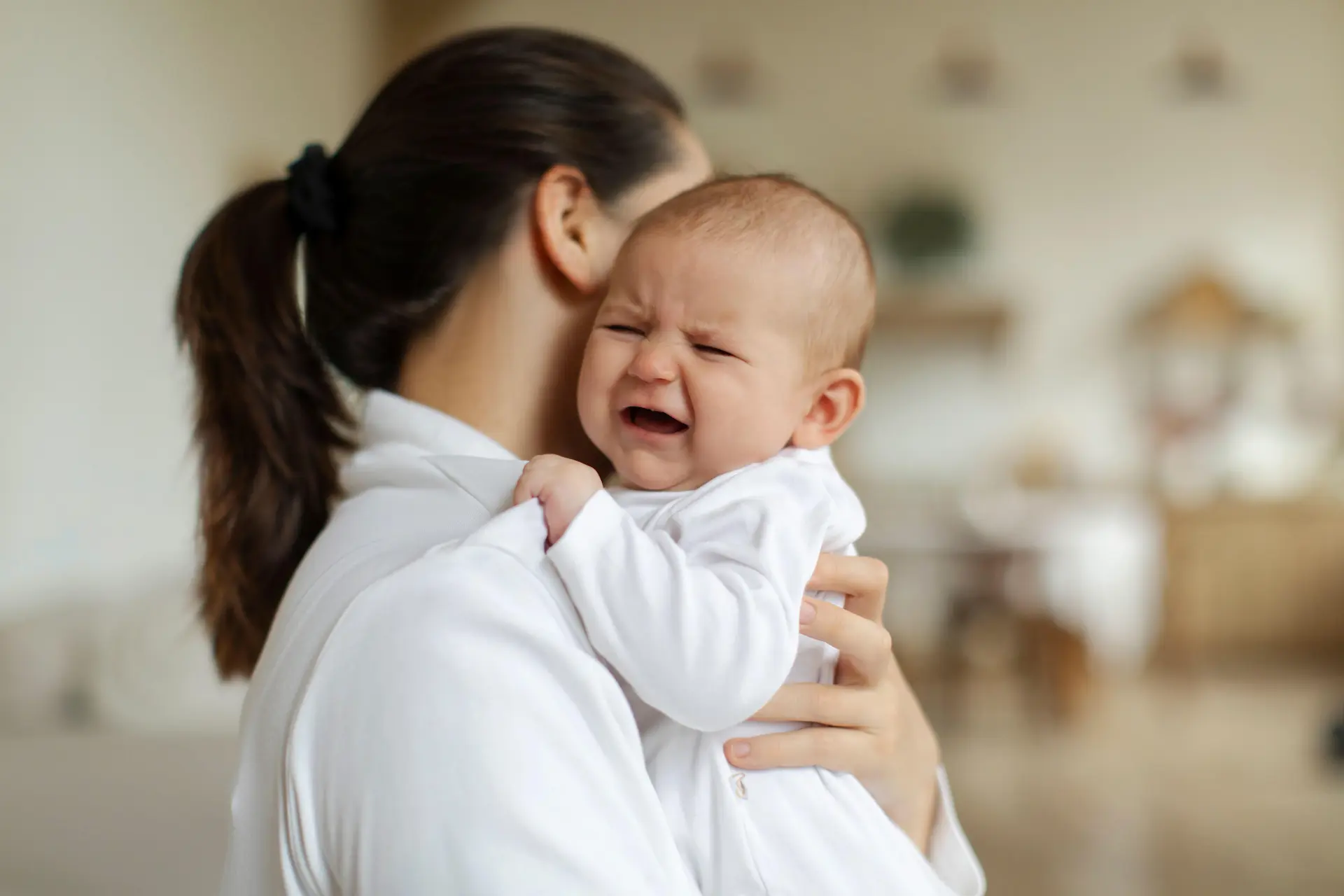 Crying baby held by mum